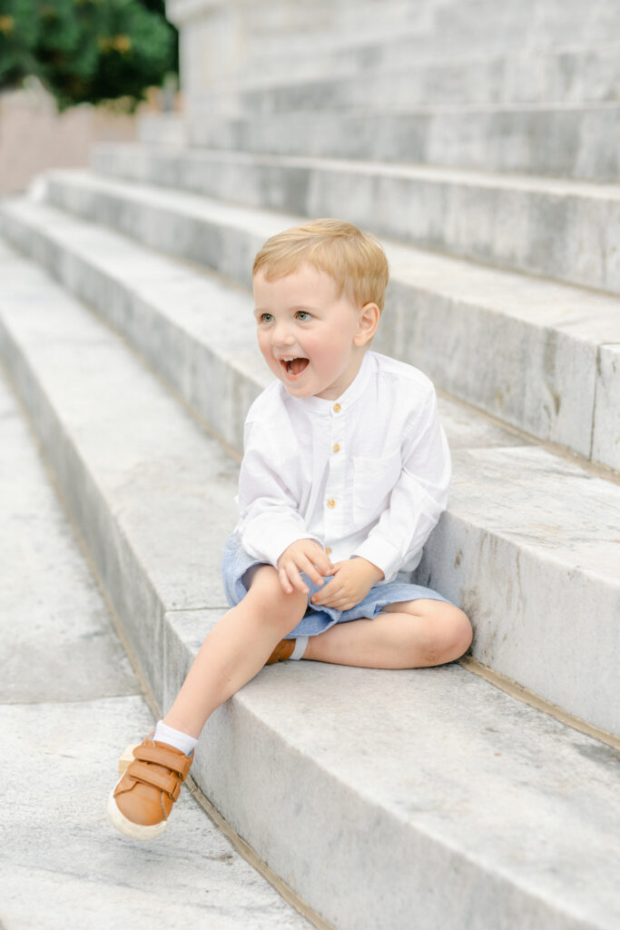a toddler laughing while sitting on a staircase

