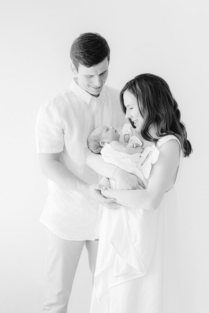 Mom and Dad holding their newborn baby during a photo session in a white studio in Vestavia, Alabama.