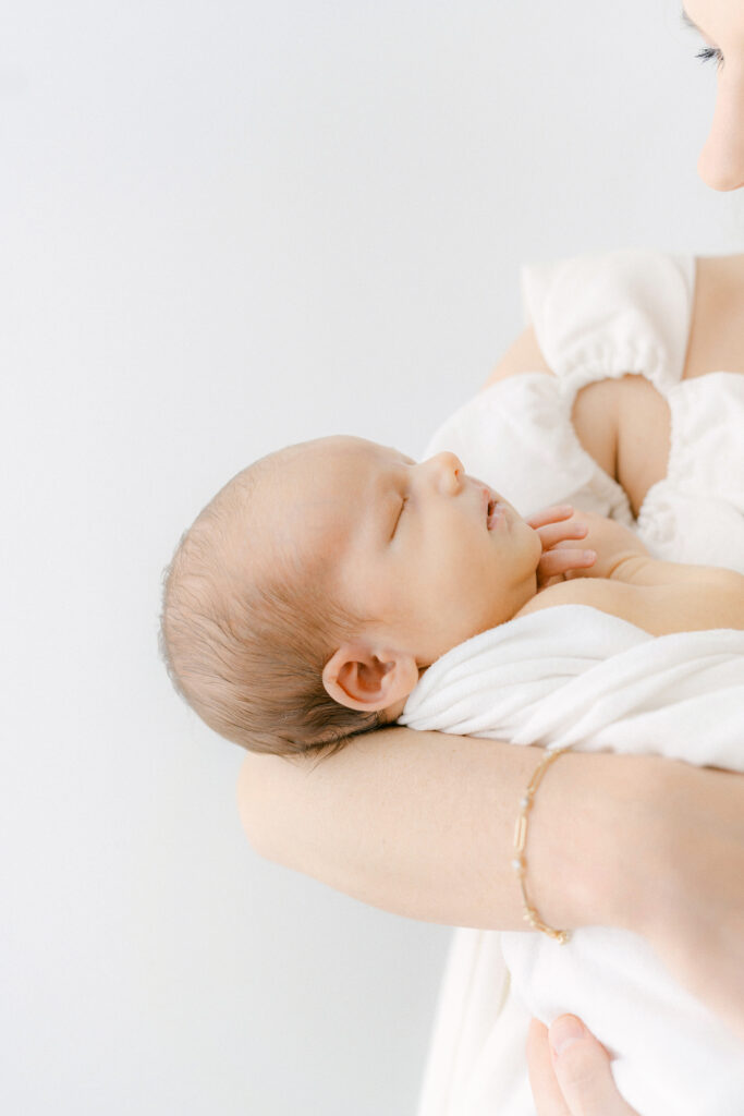 photo of a new mom holding her newborn baby in a white room.