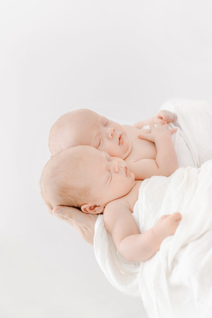 Twin, newborn, girls in Dad's hands.