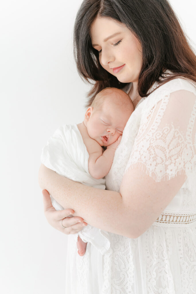 Photo of a mom holding her newborn baby, girl on her chest.