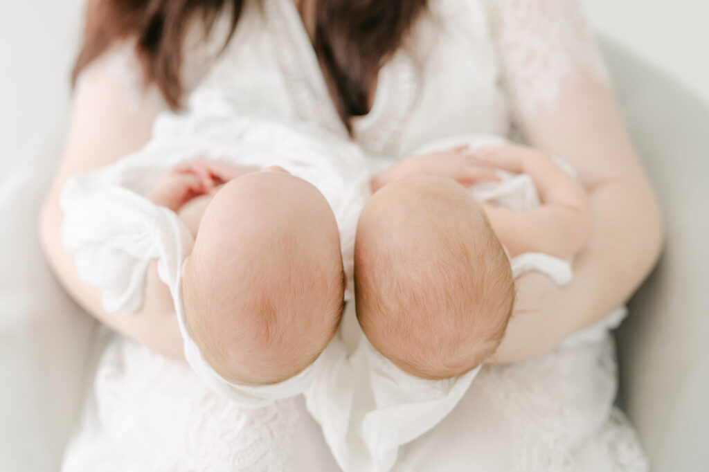 photo of the back of the heads of twin girls in their mother's hands.