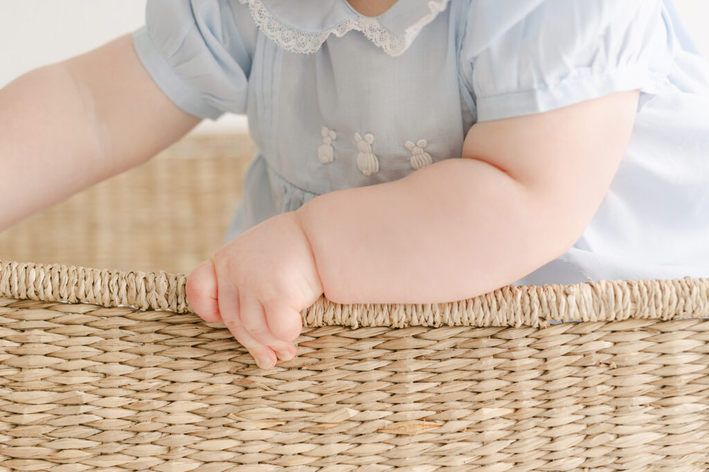 A photo of a 7 month old girls hand holding on to a basket.