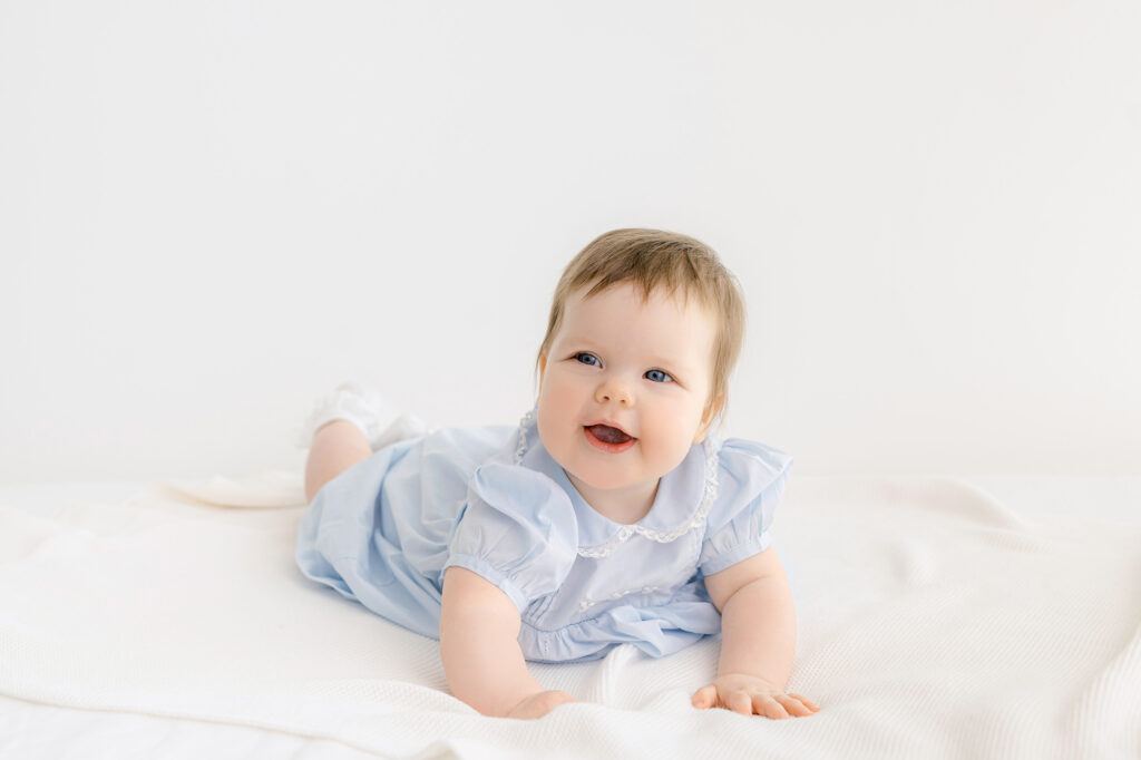 Twin girls have their photo taken on a white bed.  