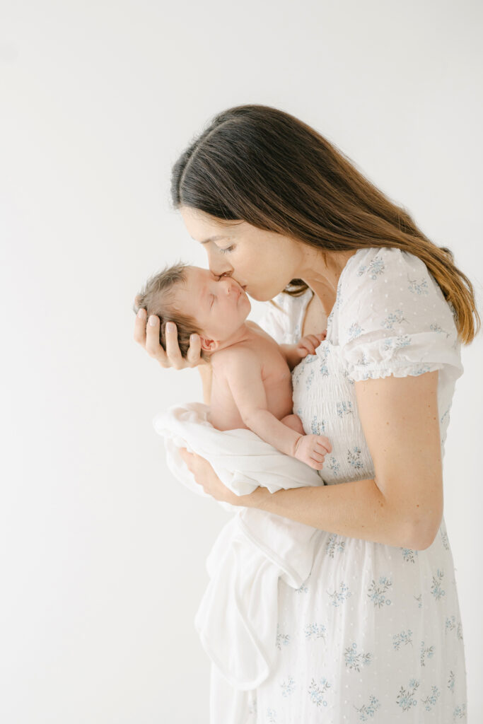 a new mom kisses her new baby lovingly on the cheek