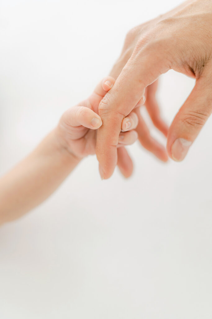 a new mom holds her babys hand