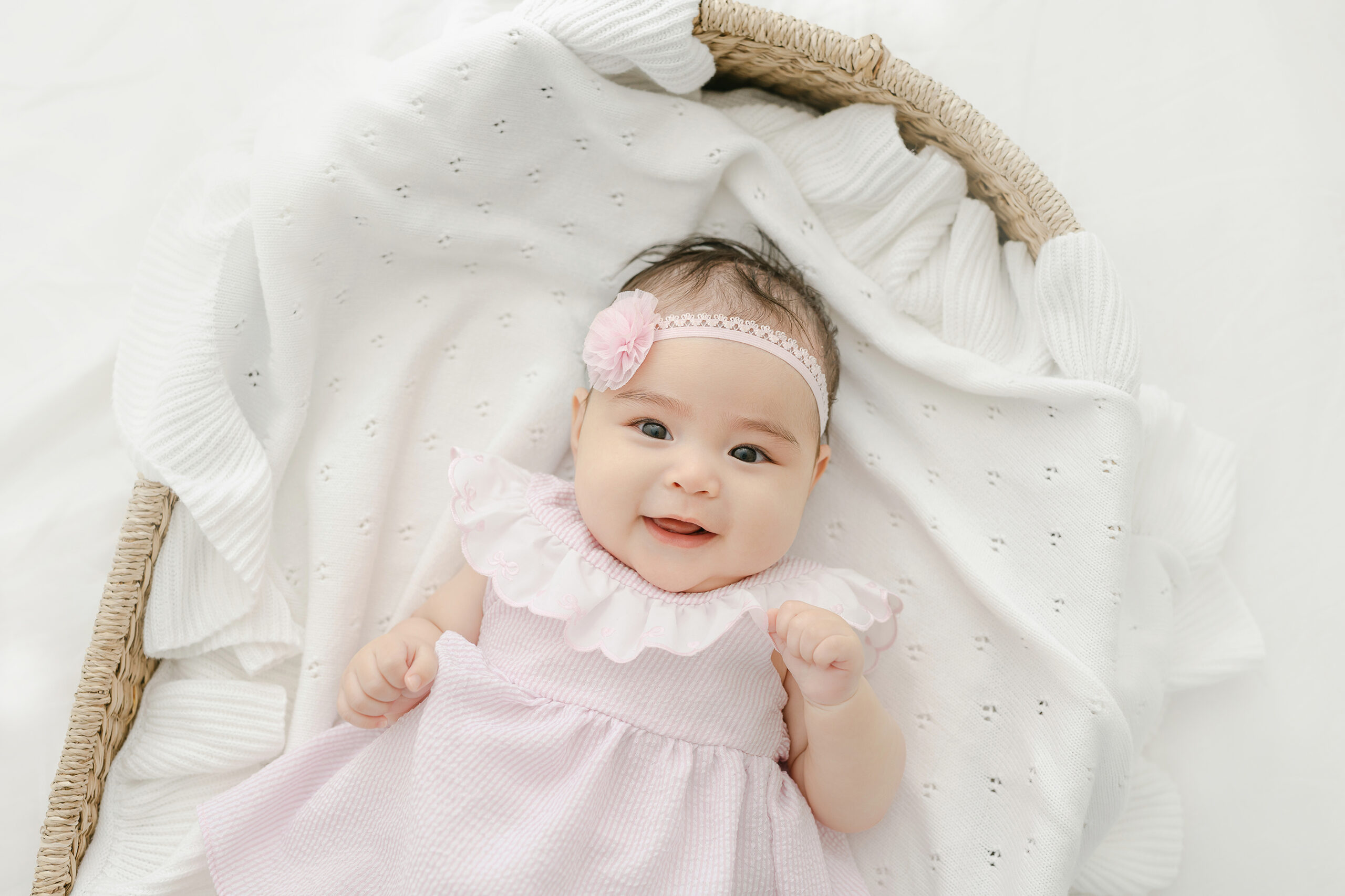 4 month old baby in a basket smiling up at the camera